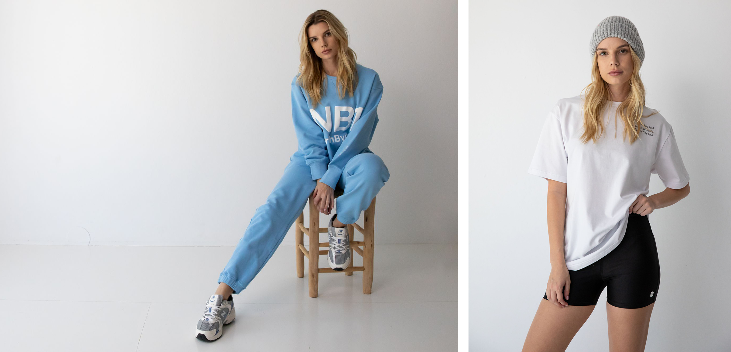 Young woman wearing a blue NorthByOne sweatshirt and sweatpants sitting on a wooden stool against a plain white background next to a woman in a white t-shirt, black shorts, and gray beanie standing against a white wall