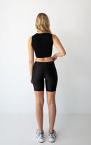 Woman with long blonde hair wearing a NorthByOne black Leyla Short Tight and black sleeveless top standing against a white background