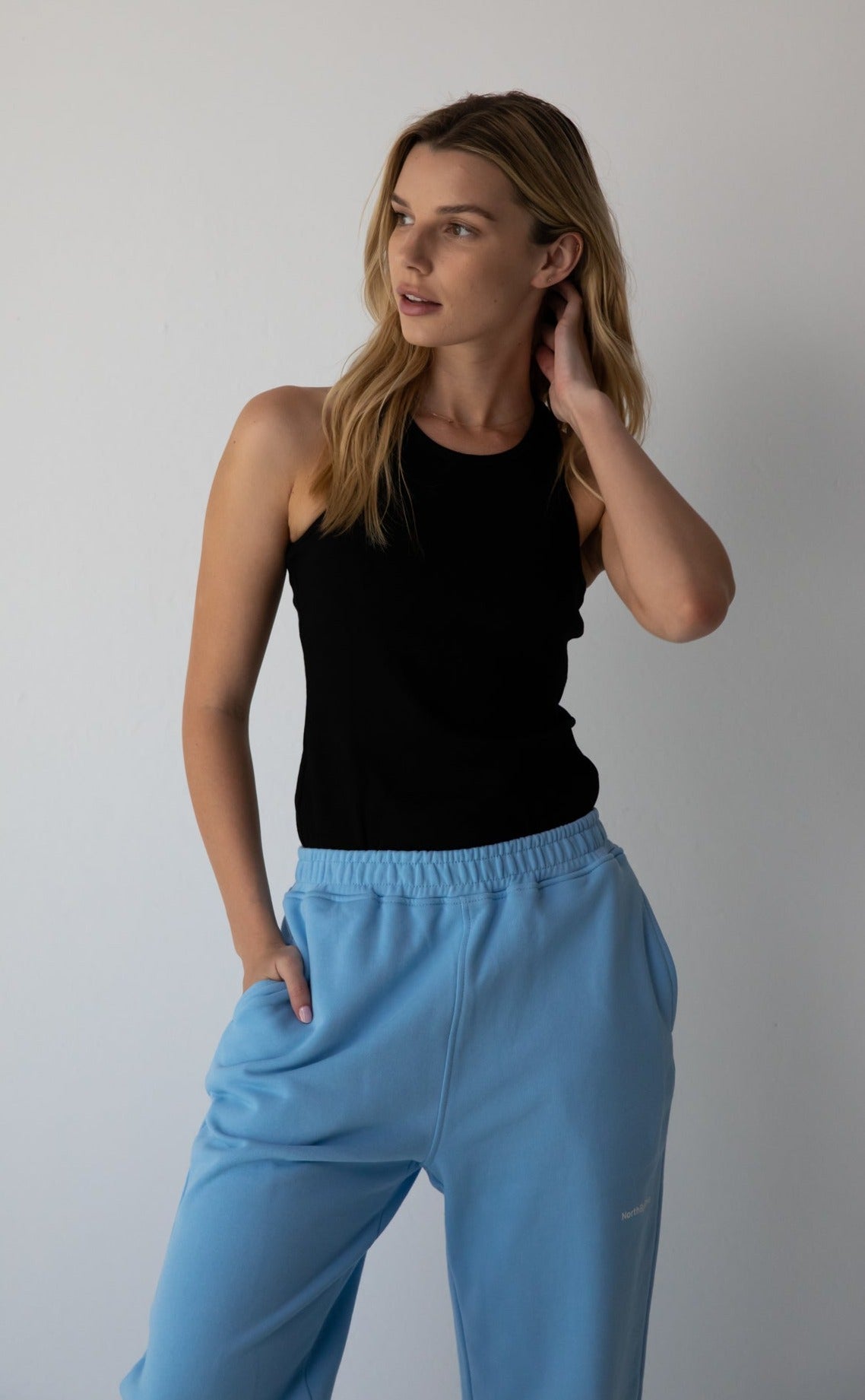 Woman wearing the NorthByOne Emma Baggy Sweat Pant in Colbalt Blue, with elasticated waistband and black sleeveless top against a plain background
