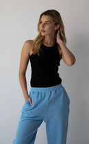 Woman wearing the NorthByOne Emma Baggy Sweat Pant in Colbalt Blue, with elasticated waistband and black sleeveless top against a plain background