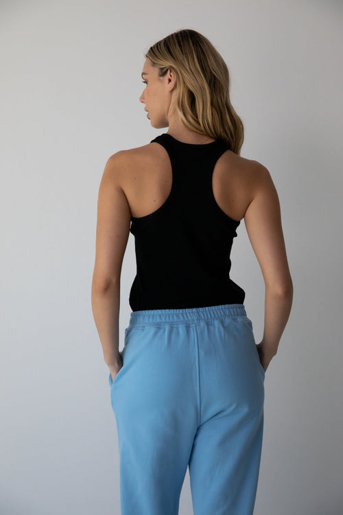 Woman wearing the NorthByOne Emma Baggy Sweat Pant in Colbalt Blue, with elasticated waistband and black sleeveless top against plain background