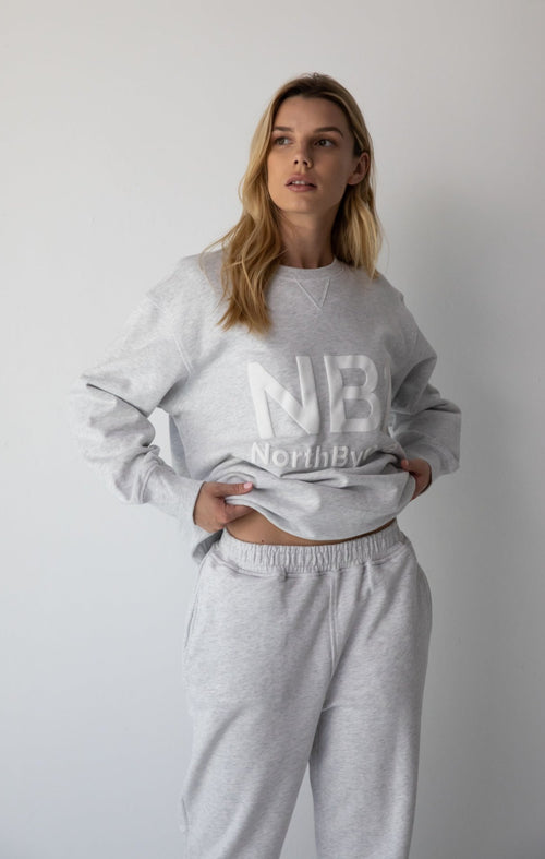 Woman wearing the NorthByOne Emma Baggy Sweat Pant in Marle Grey, with matching sweatshirt against a plain white background