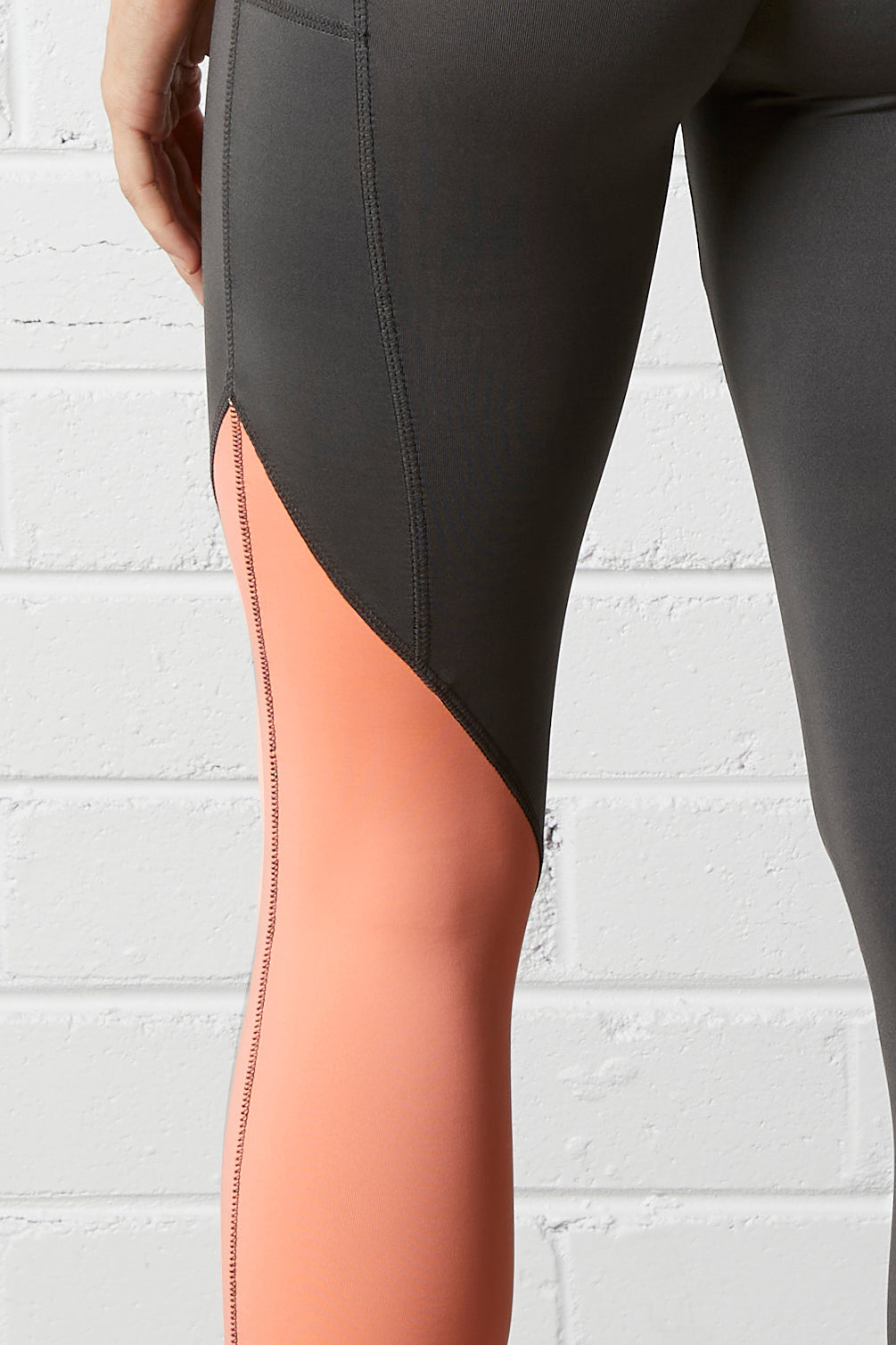 Close-up of the NorthByOn Cara Three Quarter Tight - Slate Grey / Neon Pink against white brick wall background