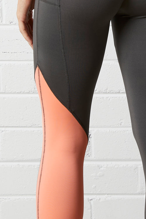 Close-up of the NorthByOn Cara Three Quarter Tight - Slate Grey / Neon Pink against white brick wall background