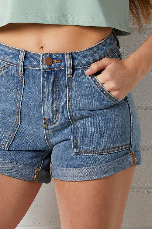 Close-up of a woman wearing a NorthByOne Charlotte Denim Short with cuffed legs and front pocket detail against a neutral background